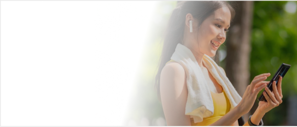 Smiling woman with earbuds, holding phone outdoors.